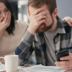 Couple stressé devant des documents bancaires refusés sur bureau