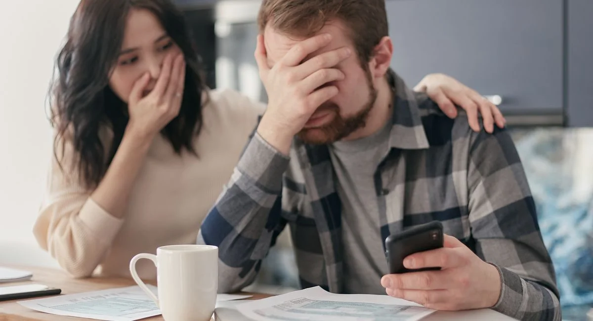 Couple stressé devant des documents bancaires refusés sur bureau