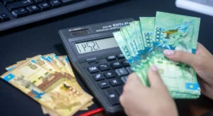 Salarié consultant sa fiche de paie avec calculatrice et ordinateur ouvert