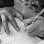 Main qui verse des pièces sur un livret marqué "retraite" sur table de bureau