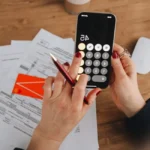 Quatre dossiers d’épargne et une calculette sur une table en bois