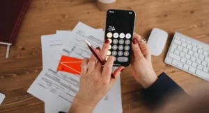 Quatre dossiers d’épargne et une calculette sur une table en bois