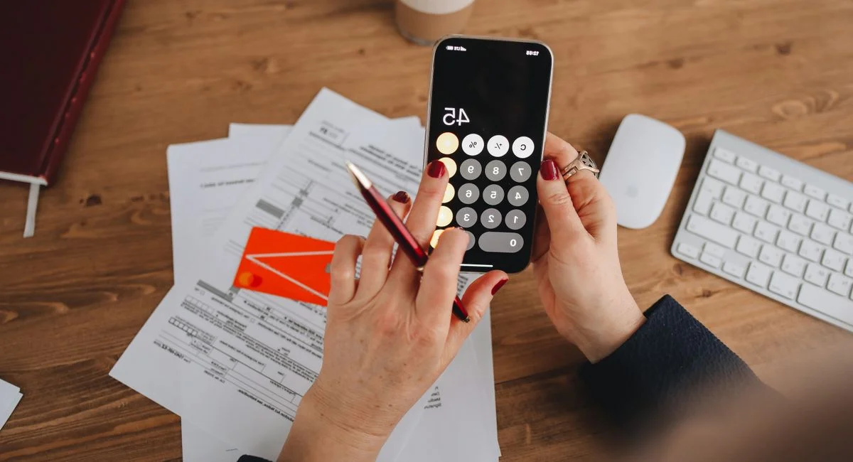 Quatre dossiers d’épargne et une calculette sur une table en bois