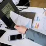 Homme en chemise devant tableau de données et équipe concentrée autour